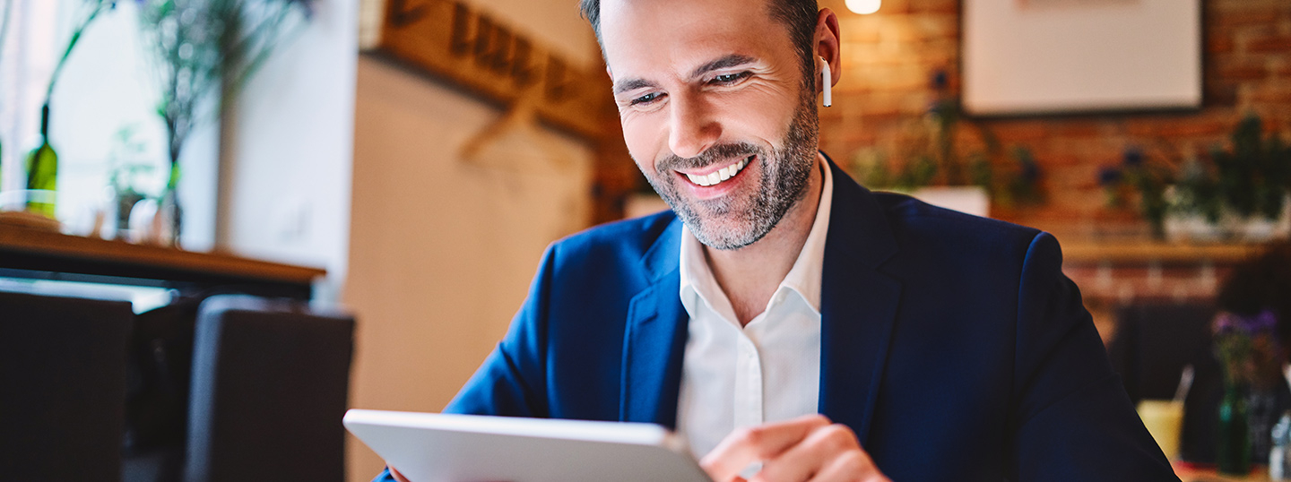 Man in suit working on his tablet in a cafe