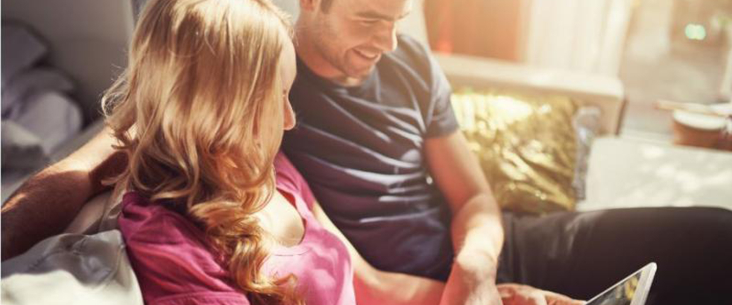 Man and woman sitting on a sofa looking at a tablet