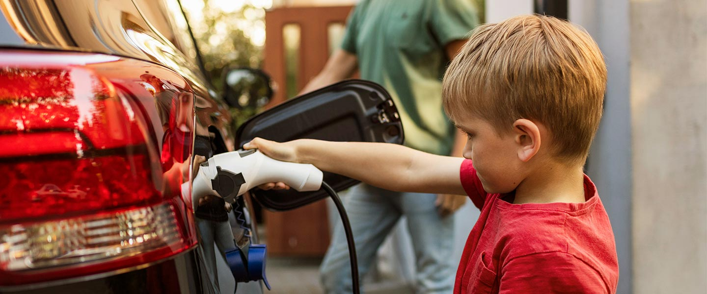 Boy plugging electric charger in to car