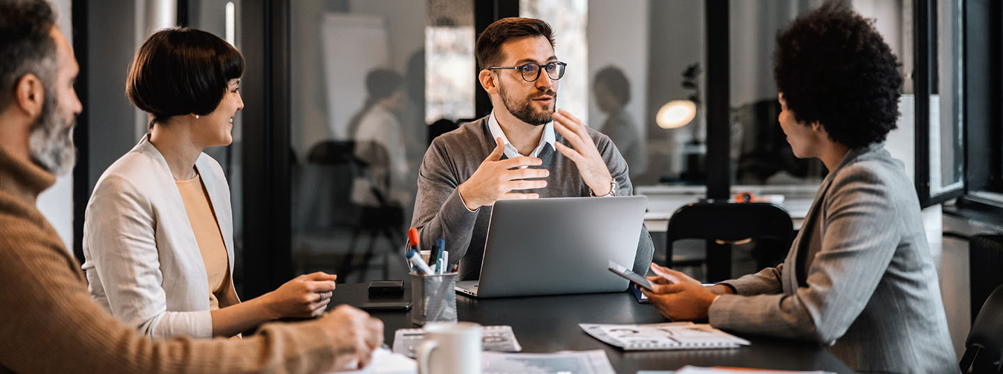 A young professional collaborating within a group of other professionals in a meeting room 